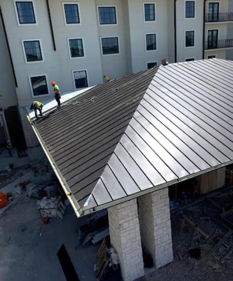 Crew installing standing seam metal roof panels on a commercial project in El Dorado